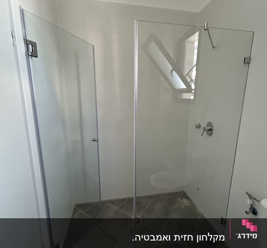 מקלחון זכוכית עם רצפת אריחים אפורים וברז מתכת